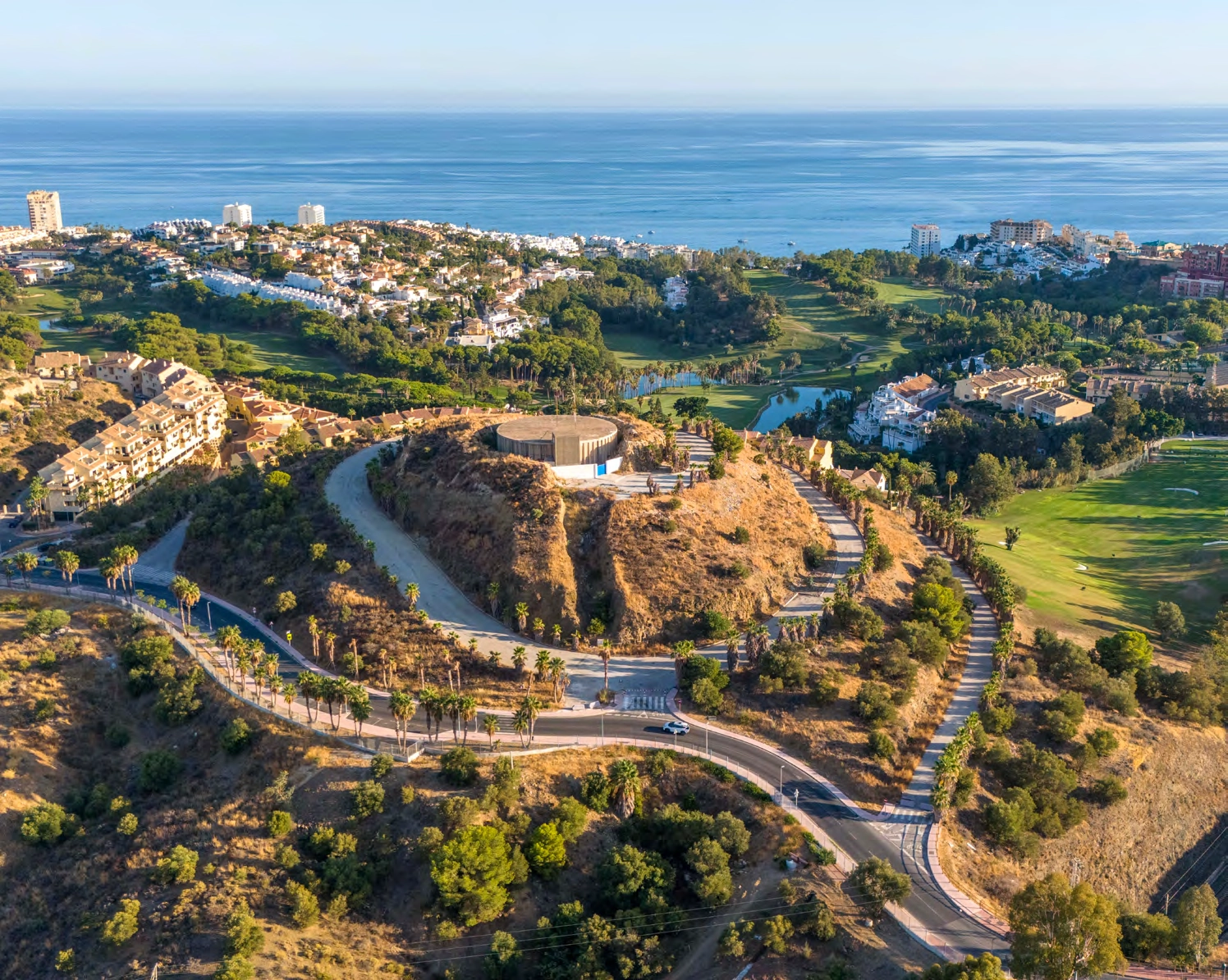Et luftfoto, der viser projektets privilegerede beliggenhed, indlejret mellem bjergene og havet.