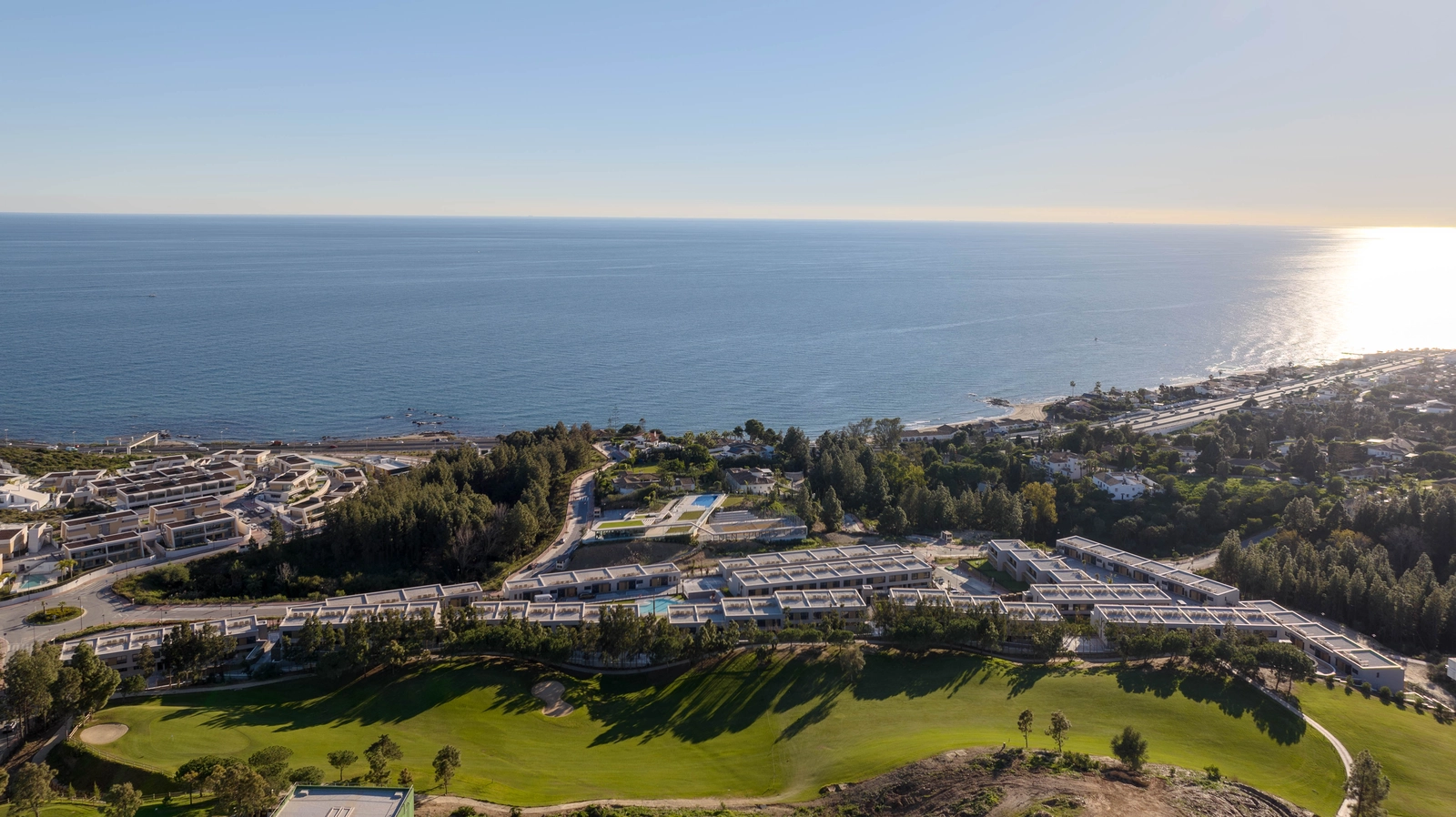 An aerial view of Evergreen Homes, perfectly situated between the green fairways of the golf course and the blue Mediterranean Sea.