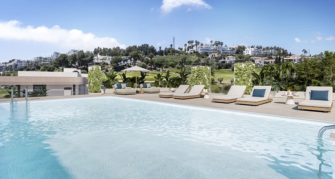 The large communal swimming pool, surrounded by sun loungers and lush greenery.