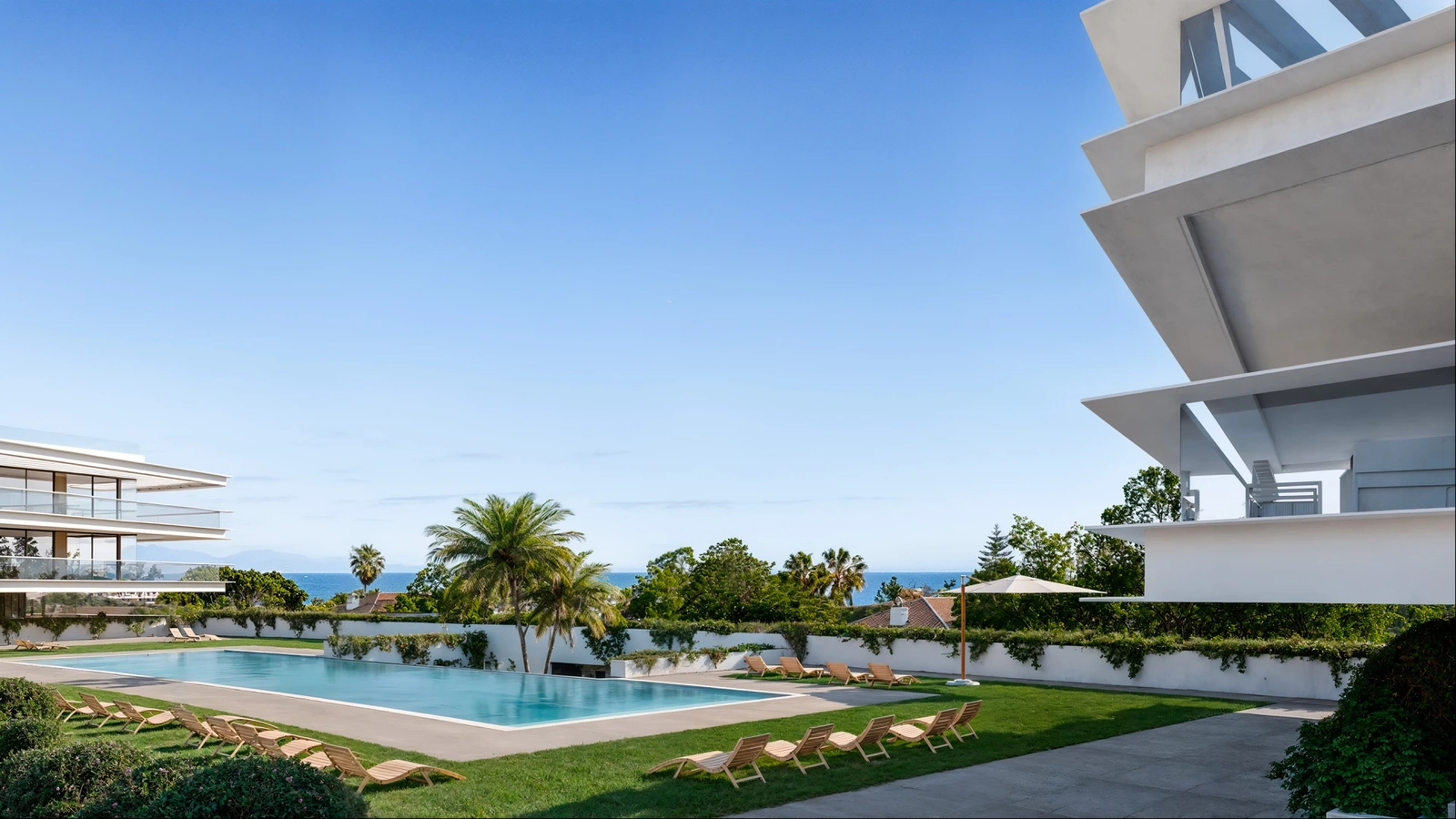 The communal swimming pool and gardens offer a tranquil escape with views towards the sea.