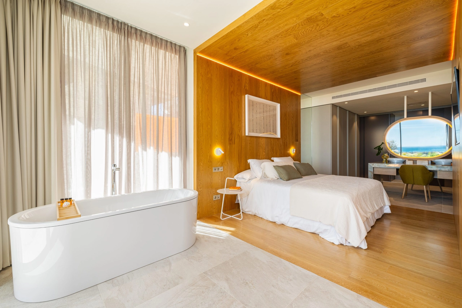 Elegant apartment bedroom complete with a freestanding bath and warm wood finishes.