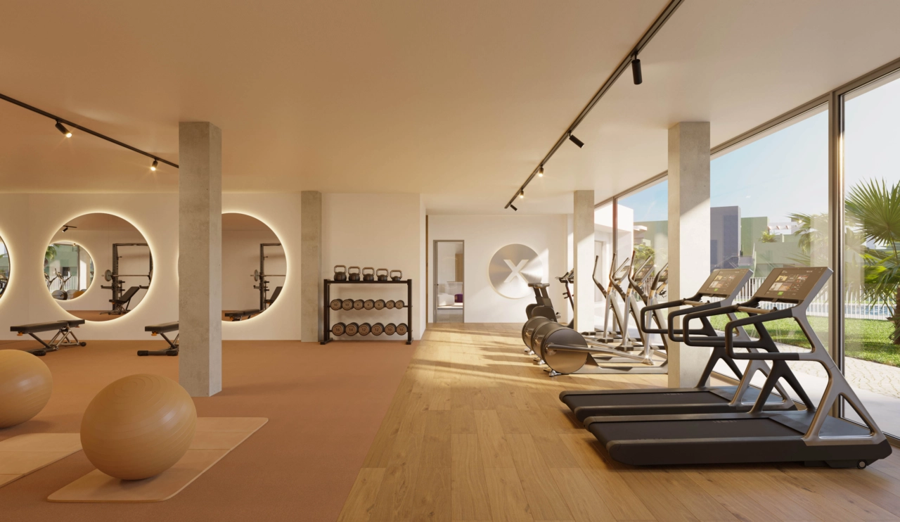 Un gimnasio totalmente equipado con grandes ventanales con vistas a los jardines y la zona de la piscina.