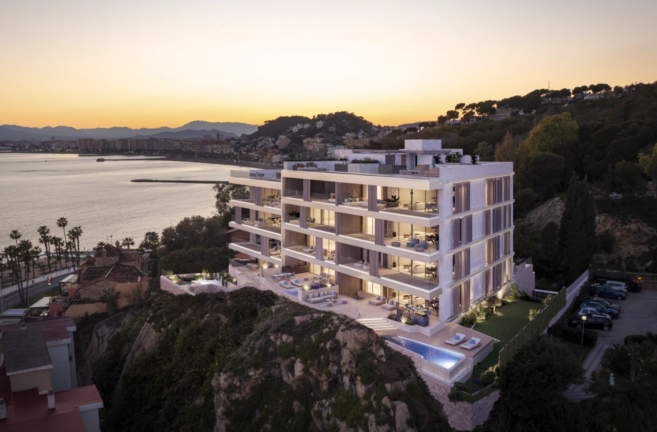 La moderna arquitectura de la promoción se ilumina bellamente al anochecer, con vistas a la costa de Málaga.